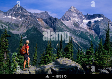 Donna trekking lungo la Abbott Ridge Trail guardando a monte Sir Donald nel Parco Nazionale di Glacier, British Columbia, Canada. Foto Stock