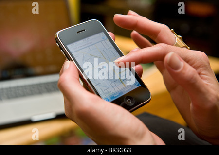 Ravvicinata di una donna caucasica la mano utilizzando l'iPhone per la navigazione GPS Foto Stock