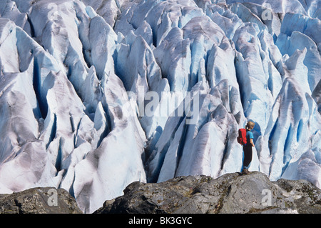 Donna in piedi sulla roccia affacciato seracchi da aggirare il Mendenhall Glacier fuori dalla città di Juneau, in Alaska. Foto Stock