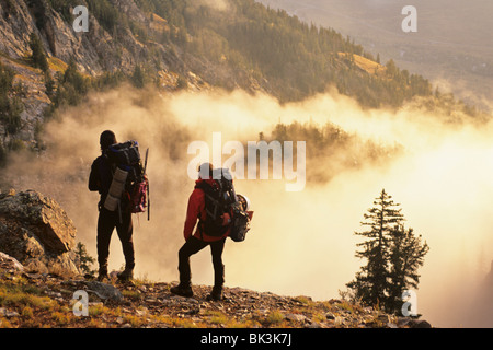 Due alpinisti pausa al di sopra di nebbia mattutina nel ghiacciaio di seguito Gulch Grand Teton picco nel Parco Nazionale di Grand Teton, Wyoming. Foto Stock
