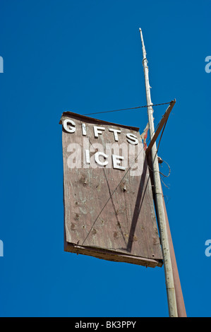 Un vecchio segno di legno per i regali e il ghiaccio si dissolve nel deserto intenso sole a tre fiumi Trading Post, Nuovo Messico. Foto Stock