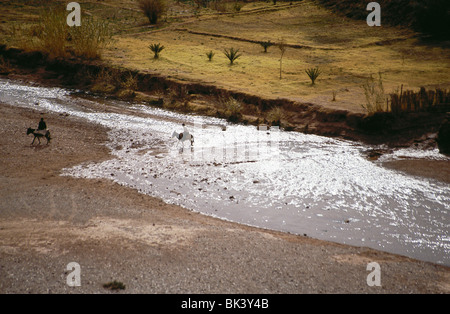 Persone a cavallo di asini su un fiume in Marocco Foto Stock