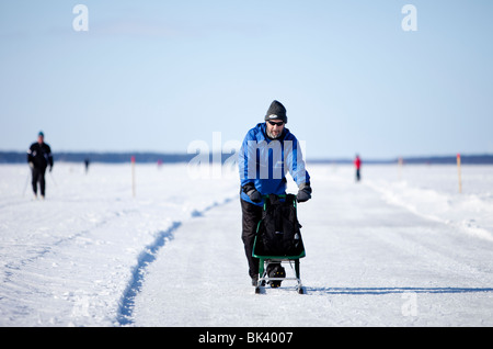 Uomo trekking con kicksled su una pista fatta di ghiaccio marino , Finlandia Foto Stock
