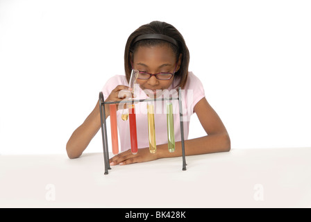 Ragazza di 10 anni, studente, facendo un esperimento scientifico con bicchieri riempiti con liquido colorato. Foto Stock