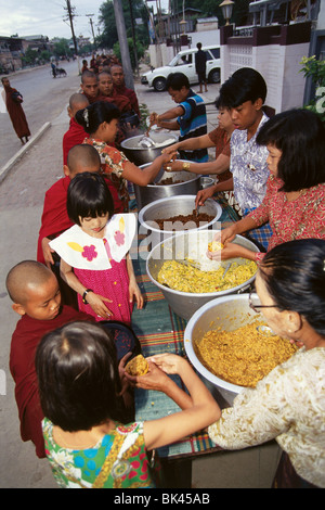 Persone che serve cibo a giovani monaci buddisti, Bagan, Mayanmar Foto Stock