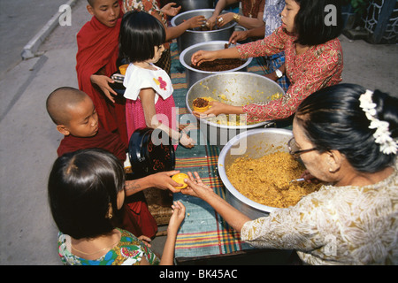 Persone che serve cibo a giovani monaci buddisti, Bagan, Mayanmar Foto Stock