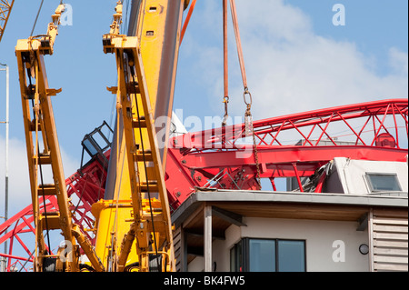 Gru a torre crollata caduto sul tetto del condominio essendo sollevata da un altro gru Foto Stock