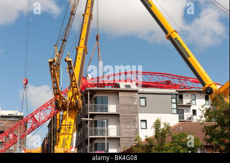 Gru a torre crollata caduto sul tetto del condominio essendo sollevata da un altro gru Foto Stock