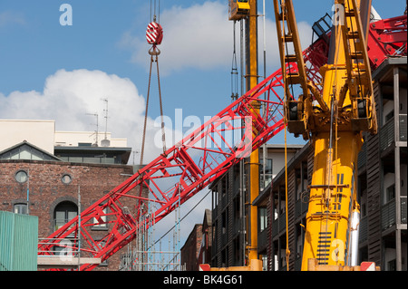 Gru a torre crollata caduto sul tetto del condominio essendo sollevata da un altro gru Foto Stock