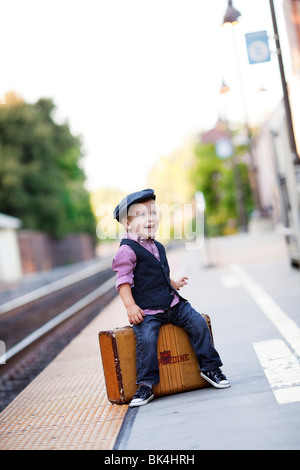 Giovane viaggiatore seduto sulla valigia Foto Stock