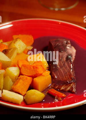 Filetto di salmone cotto in vino rosso con una salsa al vino rosso e verdure arrosto. Foto Stock