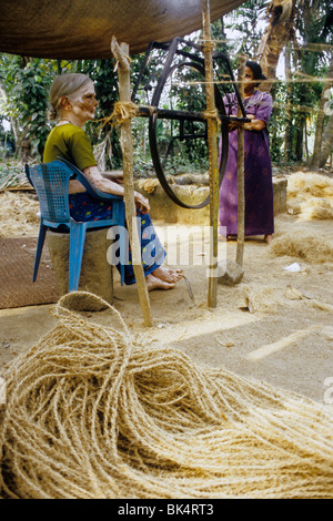 Donna che fa la corda con fibra di noce di cocco denominato "" di cocco in modo tradizionale in un villaggio backwaters Foto Stock