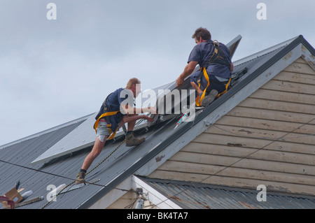 Operai di installare pannelli solari sul tetto a Hobart in Tasmania Australia Foto Stock