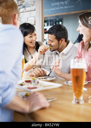 Gruppo di amici gustando un drink e stuzzichini in un ristorante Foto Stock