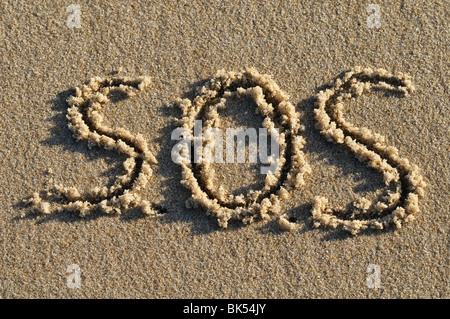 SOS scritto in sabbia Foto Stock