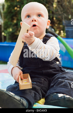Ragazzo seduto nel cortile, giocando con la costruzione in legno blocchi Foto Stock