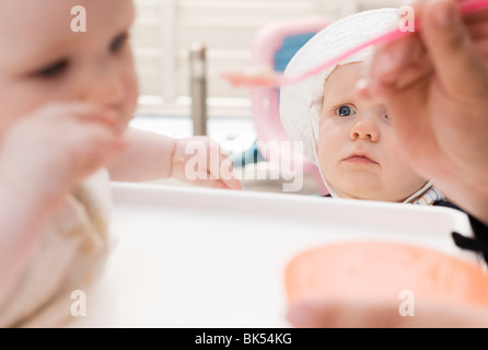 Ragazzo guardando un altro bambino essendo alimentato Foto Stock