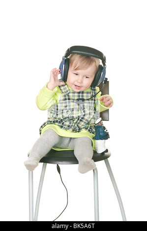 La felice bambino piccolo si siede su una sedia in cuffie auricolari con un microfono. Isolato su sfondo bianco Foto Stock