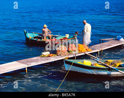 Pescatore e sua moglie la pulizia le reti da pesca in barca e molo, CORFU, ISOLE GRECHE, Grecia, Europa Foto Stock