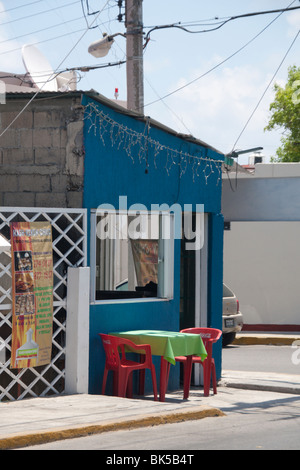 Un tavolo e sedie sedersi sul marciapiede al di fuori di un piccolo ristorante sul ciglio della strada sulla isola di Isla Mujeres,vicino a Cancun, Messico Foto Stock
