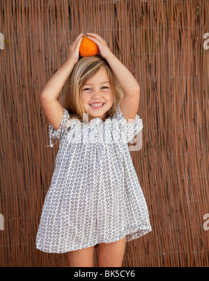Giovane ragazza in abito di Sun in possesso di un arancione sul suo capo