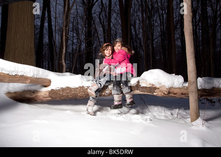 Gemelle che abbraccia ogni altro nella neve Foto Stock