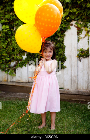 Giovane ragazza in sundress con grappolo di palloncini