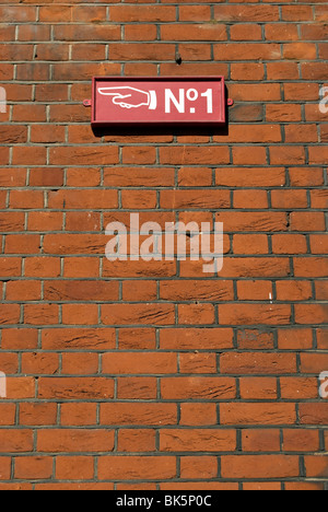 Segno su un muro di mattoni rossi con immagine di mano per indicare un numero di un indirizzo stradale, a Chelsea, Londra, Inghilterra Foto Stock