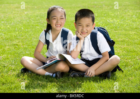 Gli studenti della scuola elementare lettura sull'erba Foto Stock