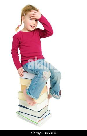 Piena isolati studio immagine da un giovane bambino seduto su alcuni libri Foto Stock