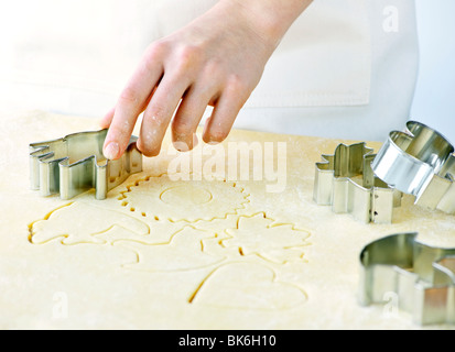 Il taglio di forme dei cookie in impasto arrotolato con taglierina Foto Stock