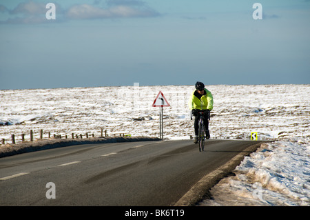 Ciclista sulla A57 Snake pass road in inverno, vicino a Glossop, Peak District, Derbyshire, England, Regno Unito Foto Stock