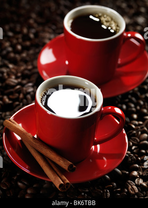 Rosso di due tazze di caffè in chicchi di caffè sfondo Foto Stock