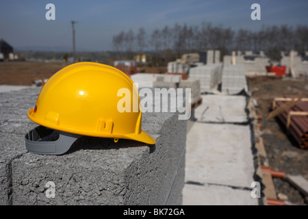 Elmetto seduto su una pila di brezza edificio in calcestruzzo blocchi sul fermo costruzione dell'edificio sito in Irlanda del Nord Regno Unito Foto Stock