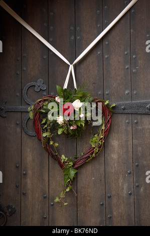 A forma di cuore ghirlanda di vimini con fiori e nastro Foto Stock