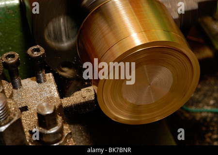 La rotazione di un pezzo di barra di ottone su un tornio utilizzando un coltello utensile di tornitura. Foto Stock