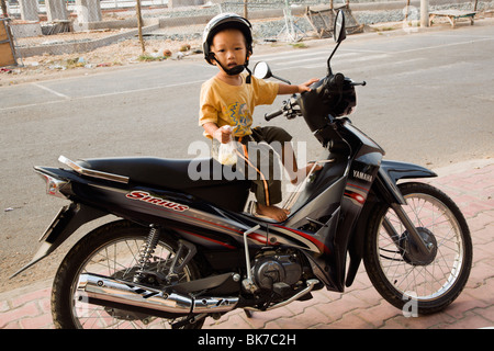 Molto giovane motorbikedriver in attesa per la mummia dal mercato giornaliero in Ha Tien Delta del Mekong Vietnam Foto Stock