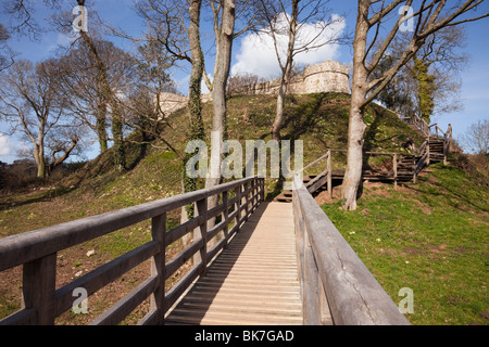 Llangoed, Isola di Anglesey (Ynys Mon), il Galles del Nord, Regno Unito. Passerella in legno attraverso il fossato intorno a Castell Aberlleiniog rovine del castello Foto Stock