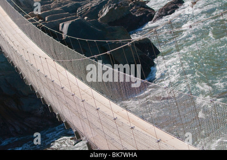 Ponte di sospensione per trekker oltre un infuria la foce Foto Stock
