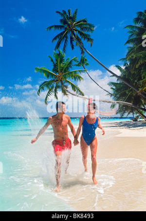 Matura in esecuzione attraverso la riva onde lungo arenile sull isola tropicale Foto Stock