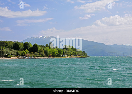 Il lago di Garda su una fresca mattina di primavera con onde instabili e distante un vista del Monte Baldo con la neve sulla sommità Foto Stock