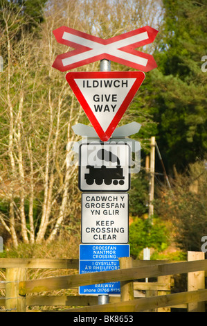 Welsh bilingue Inglese e cartelli di avvertimento in corrispondenza di un passaggio a livello, Welsh Highland Railway, Nantmor, Snowdonia, Galles del Nord, Regno Unito Foto Stock