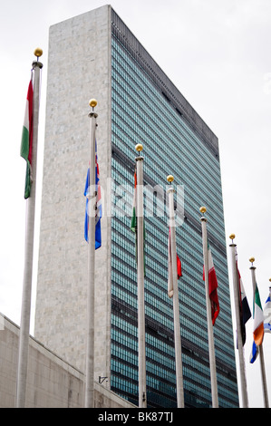 Sede delle Nazioni Unite Flags New York City // NEW YORK, Stati Uniti — una serie di bandiere colorate che rappresentano gli stati membri delle Nazioni Unite battono di fronte all'iconico edificio del Segretariato delle Nazioni Unite, la struttura principale degli uffici del complesso delle Nazioni Unite a New York City. Questa impressionante dimostrazione di unità internazionale si trova sullo sfondo di un'architettura elegante e modernista che è diventata un simbolo della diplomazia e della cooperazione globale. Foto Stock
