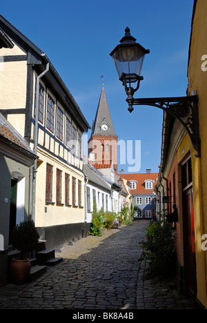 Strada di ciottoli nella storica città di Aalborg, Ålborg nel retro la Frue Kirke chiesa, Nordjylland regione, Danimarca, SCA Foto Stock