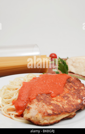 La Turchia milanese bistecca su spaghetti con sugo di pomodoro e un pezzo di formaggio parmigiano reggiano, gli spaghetti in vetro Foto Stock