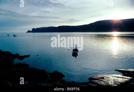Pescatore Inuit getta un net nel porto del piccolo villaggio di artico di Pangnirtung, Isola Baffin, Nunavut, Canada Foto Stock