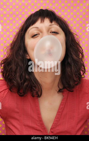 Giovane donna soffiando bubble gum Foto Stock