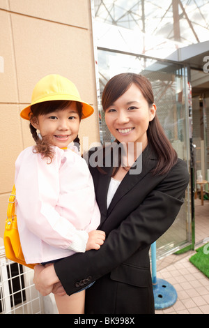 Donna di lavoro tenendo la figlia Foto Stock