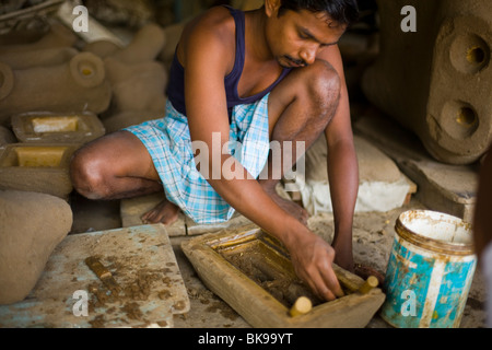 Un artigiani stampi argilla locale intorno all'immagine in cera di un diety per essere fusa in bronzo Foto Stock