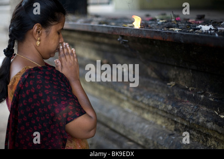 Una donna offre preghiere dopo accendendo una lampada ad olio al di fuori del tempio Murugan in Swamimalai, Tamil Nadu, India Foto Stock